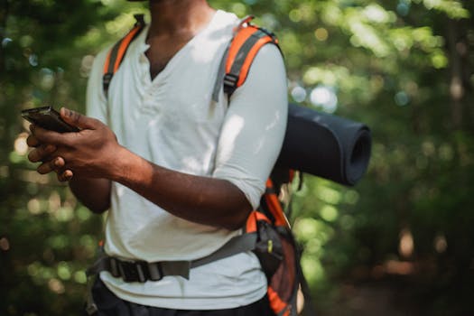 Essential Dog Hiking Gear: Complete Guide to Outdoor Adventure Equipment A man in the forest checking his smartphone during a summer hike.